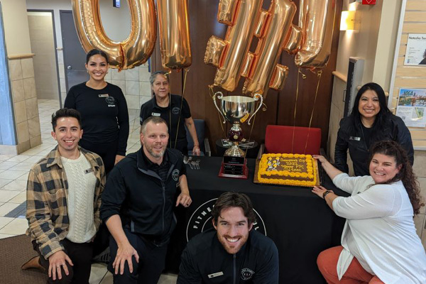 Staff celebrating with trophy and cake at Best Gym in Old Town.