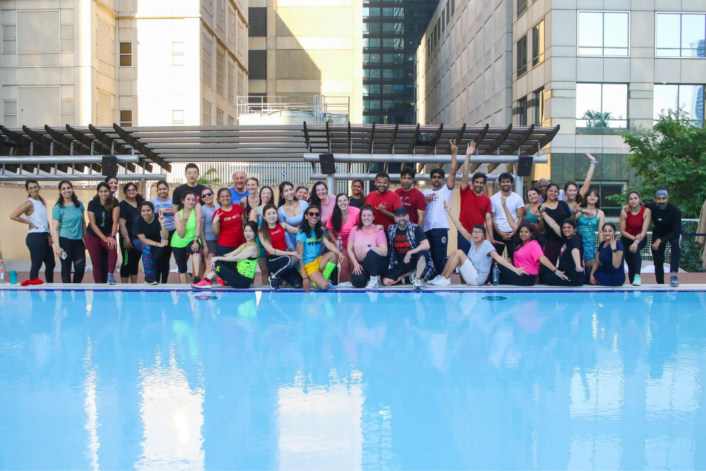 Group fitness dance class on outdoor pool deck.