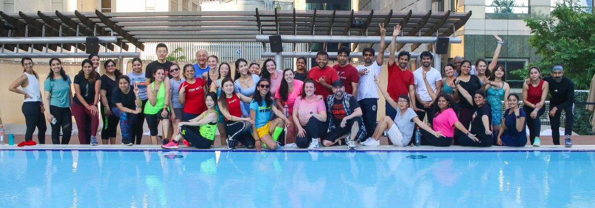 Group fitness dance class on outdoor pool deck.