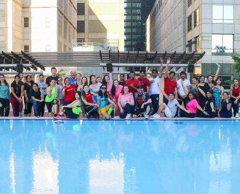 Group fitness dance class on outdoor pool deck.