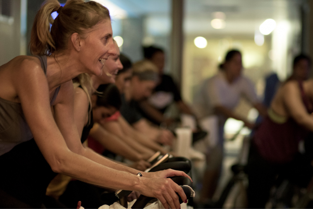 Members smiling on bikes during spin class.