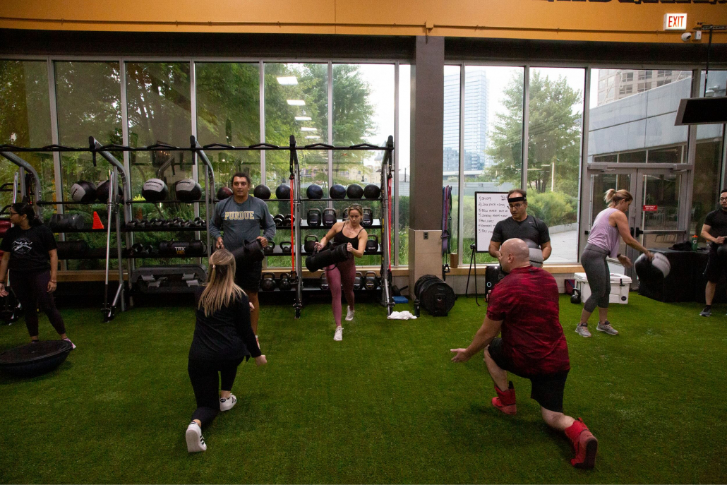 Small group training class performing HIIT exercises on the indoor turf.