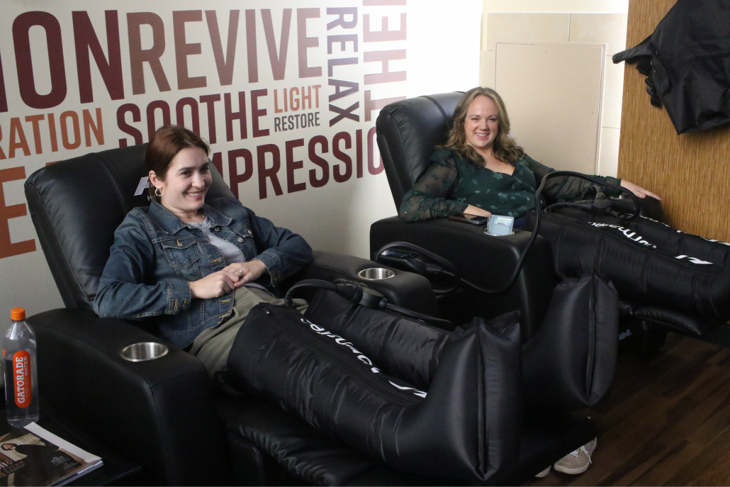 Female members using compression boots in the FFC West Loop recovery lounge.