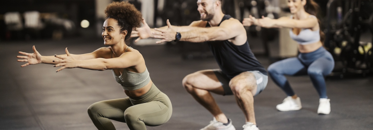 Sporty friends doing squat endurance in a gym together.