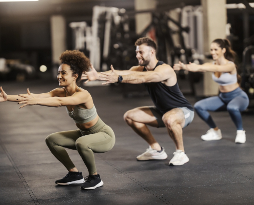 Sporty friends doing squat endurance in a gym together.