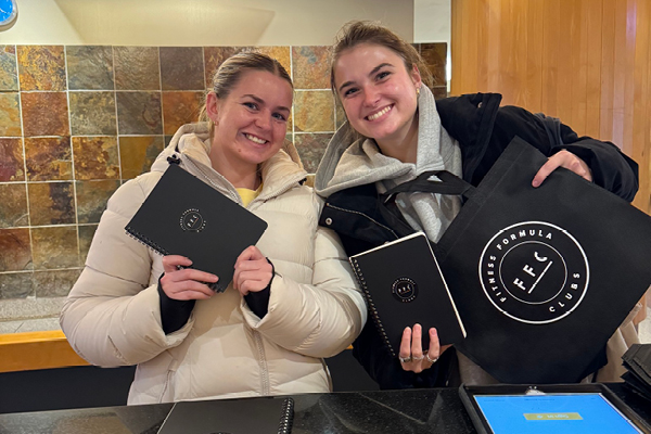 Two Gold Coast members with FFC Merch - Backpack and Notepad