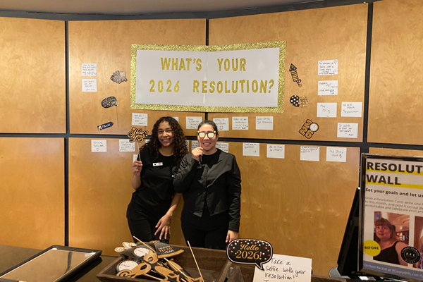 two Gold Coast employees posed with a 'what your 2026 resolution' backdrop