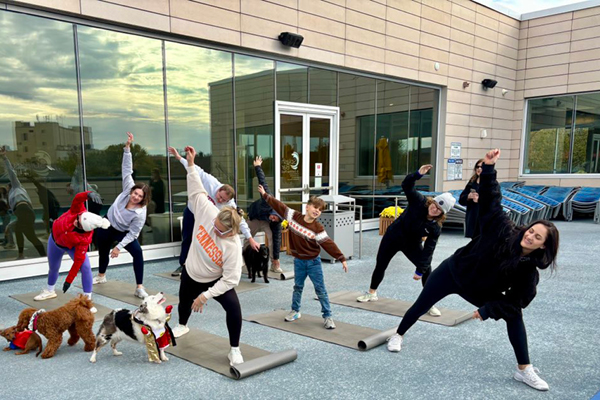 FFC Park ridge instructor and members on their outdoor rooftop pool deck doing doggie yoga